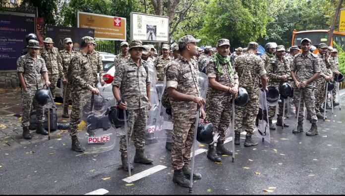 A news photograph showing police barricades and security personnel near a major road in New Delhi.